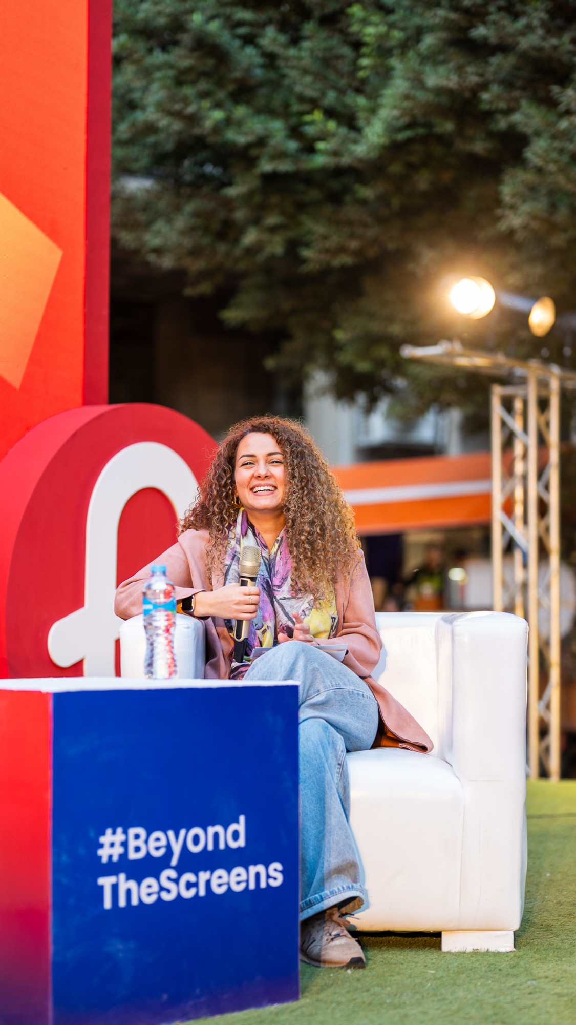 Nourhan Maher speaking on stage at an outdoor event